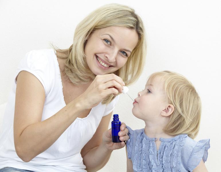 Happy woman giving medicine to child